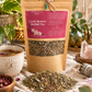 Cycle Restore | Herbal Menstrual Tea* 7chakrasrus with scattered herbs and a cup of tea