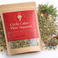 Herbal supplement package labeled 'Cycle Calm + Flow Support' with a wooden spoon and herbs on a white background.